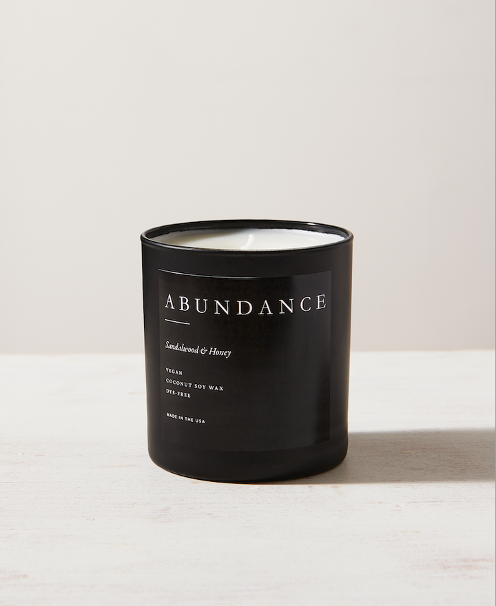 Black glass 11oz soy candle with sandalwood and honey scent, offering 90 hours of burn time.