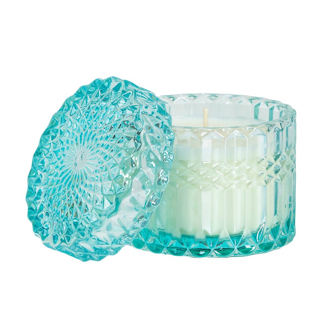 A tropical-scented soy candle in a turquoise crystal glass, with scents of Yuzu and tiger lily.