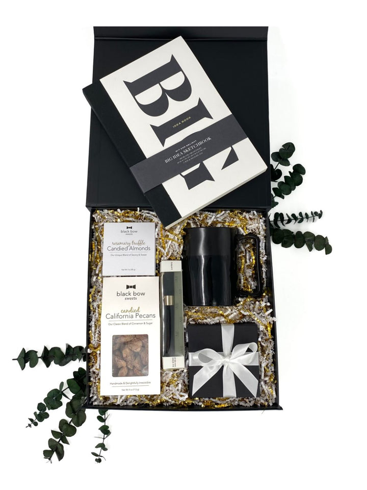 Big Ideas Gift Box with sketchbook, abundance candle, black mug, pen, and gourmet snacks in black World of Gifting magnetic keepsake box. 