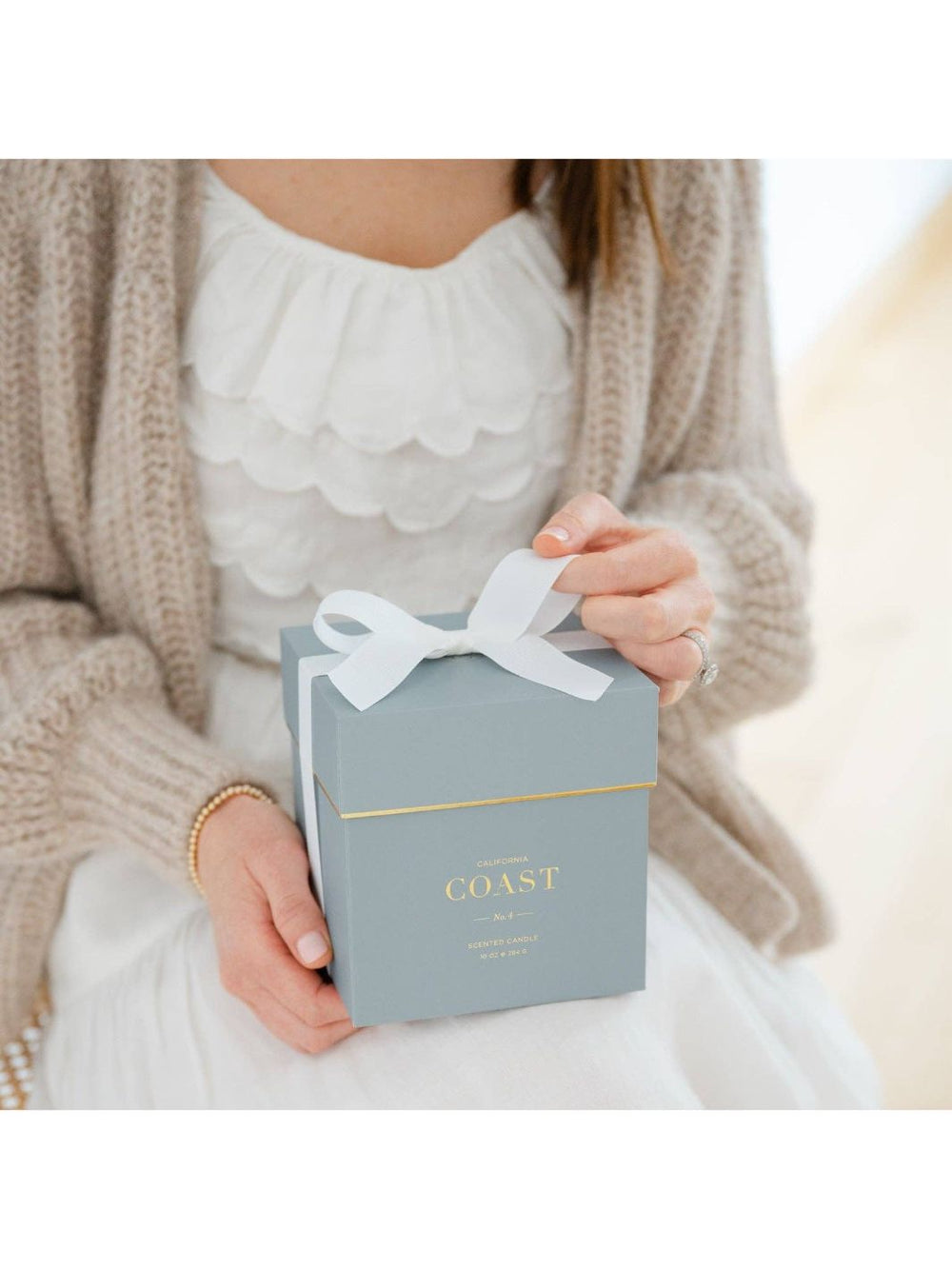 Soy-blend candle with gold detailing, packaged in a gorgeous blue gift box tied with a white grosgrain ribbon.