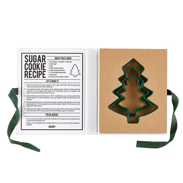 Green silicone cookie cutters in the shape of a tree inside gift box with sugar cookie recipe. 