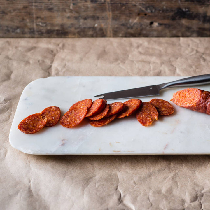 Close up of Di Bruno Brothers Sicilian Style Pepperoni sliced on a cutting board.