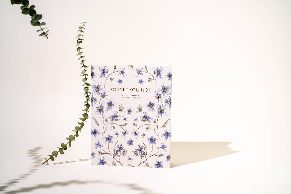 Pretty image of Forget You Not journal standing up with a eucalyptus stem as a prop. 