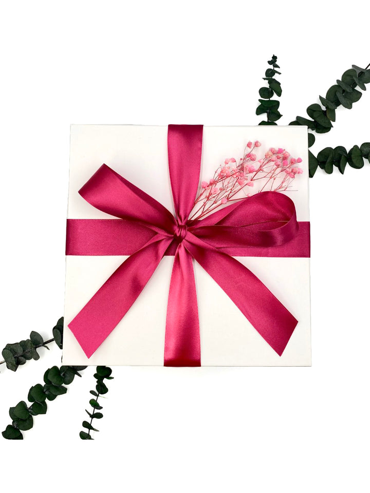 Exterior of Fuchsia Inspiration Gift Box wrapped in fuchsia colored satin ribbon with pink babies breath floral accents.