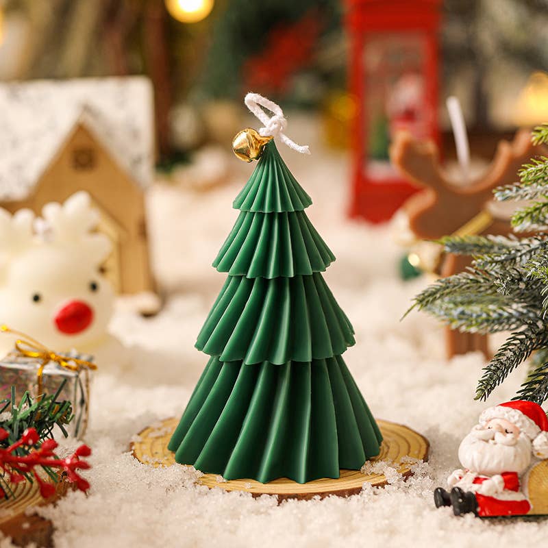 Green Christmas tree candle surrounded by holiday decorations.