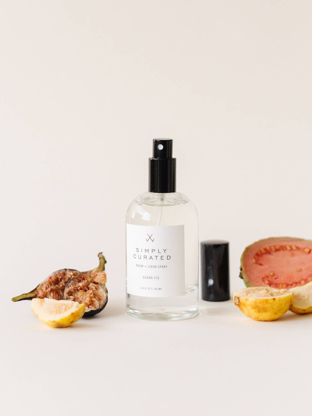 Guava Fig Room + Linen Spray bottle displayed alongside fresh guava, figs, and lemons, highlighting its fragrance notes.