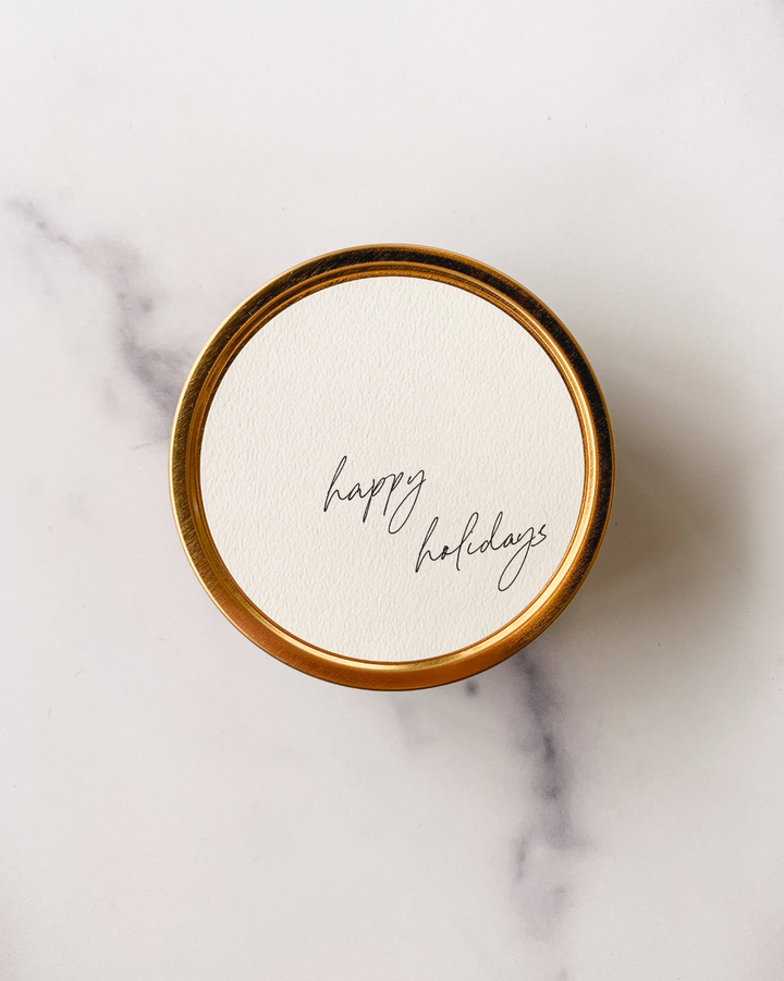 Happy Holidays Holiday Candle Tin in gold with textured paper label in guava fig scent.