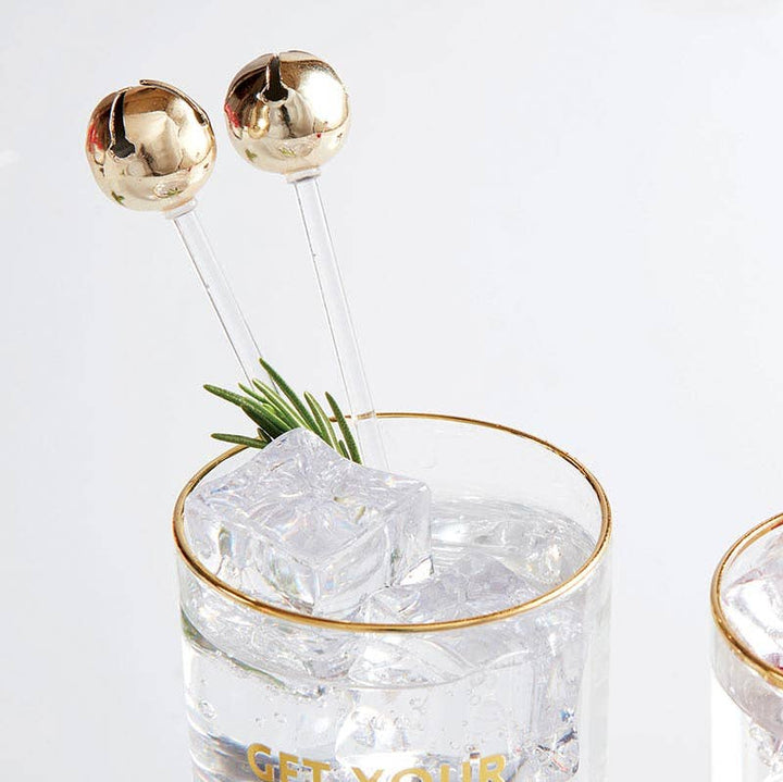 Jingle Bell Stir Sticks in holiday cocktail glass, showing festive design.