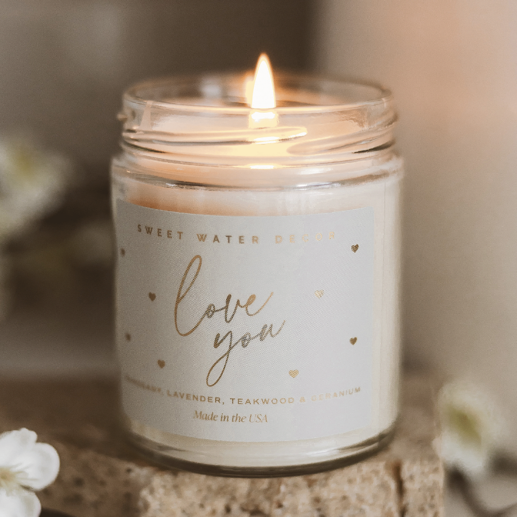 A lit Love You Candle, casting a warm and romantic glow.