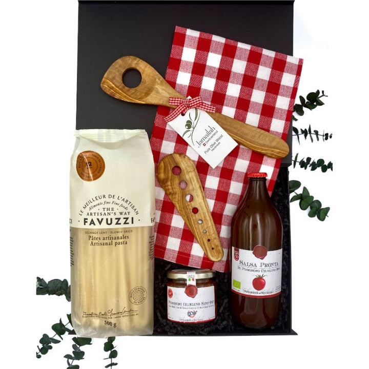 Contents of the Mama Mia Gift Box, including bucatini pasta, tomato sauce, semi-dried cherry tomatoes, herb stripper, pasta spoon, and gingham kitchen towel.