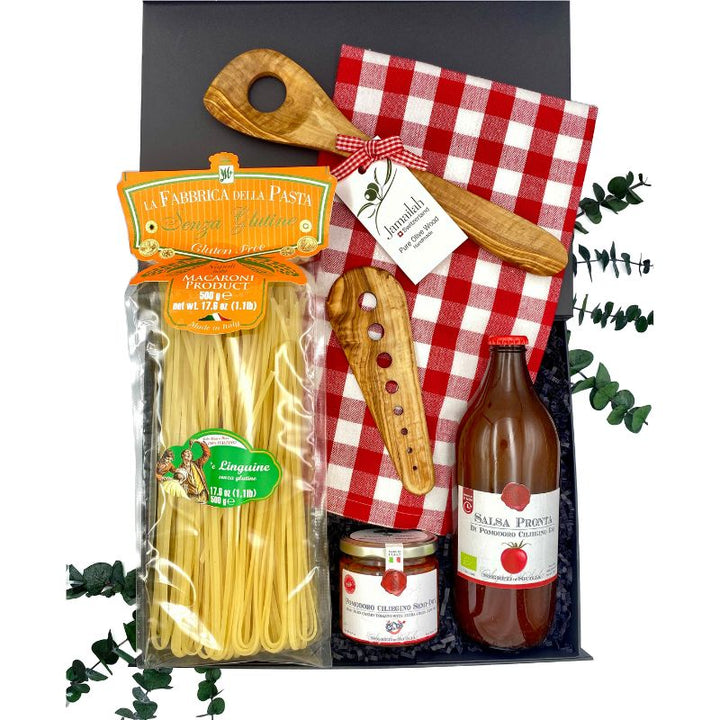 Contents of the Mama Mia Gluten Free Gift Box, including gluten-free linguine, tomato sauce, semi-dried cherry tomatoes, herb stripper, pasta spoon, and gingham kitchen towel.