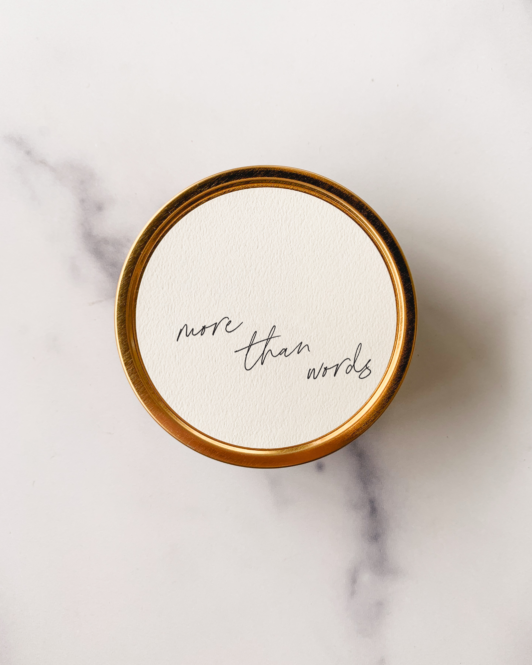 "More Than Words" Travel Candle in a gold tin with a textured paper label.