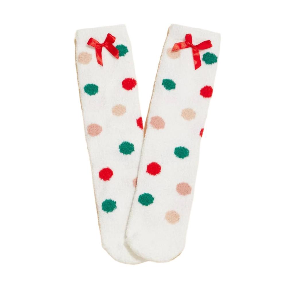 White fuzzy socks with colorful red, green, and tan polka dots, finished with a festive red bow, front view.