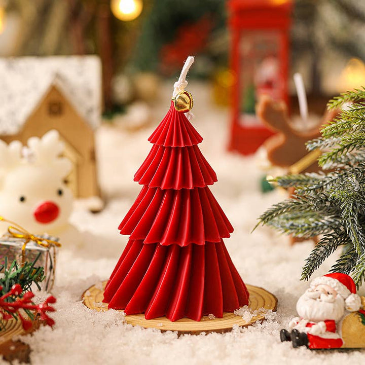 Red Christmas tree candle surrounded by holiday decorations.