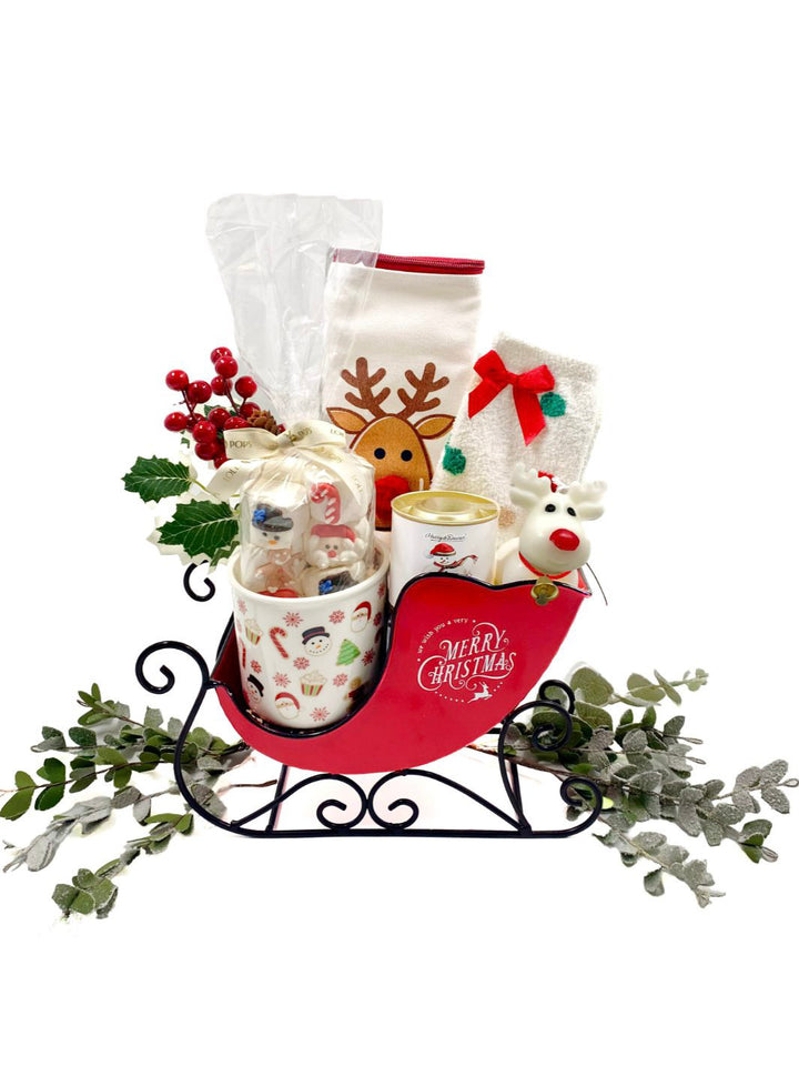 Sleigh Ride Gift Set displayed with a vintage red sleigh, reindeer pouch, and festive holiday treats.