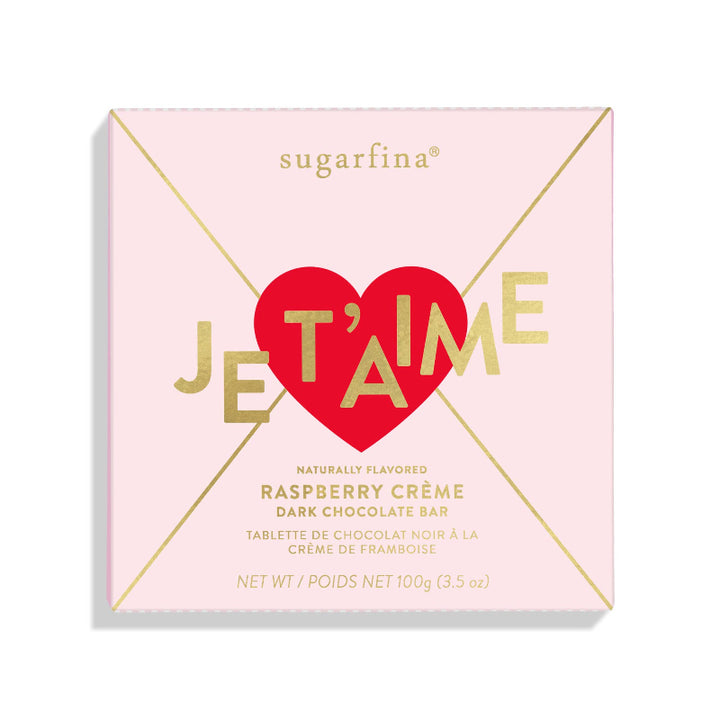 Sugarfina Dark Chocolate Raspberry Crème Bar in pink and gold envelope-style packaging with “Je T’aime” in gold over a red heart.