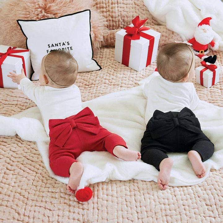 Two babies wearing bow leggings in red and black color ways.