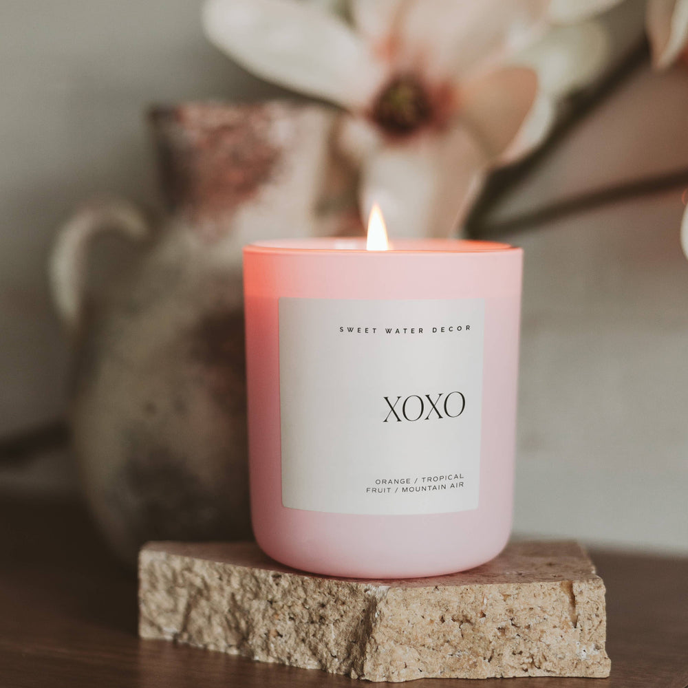 XOXO Soy Candle in a matte pink jar, placed in a modern setting.